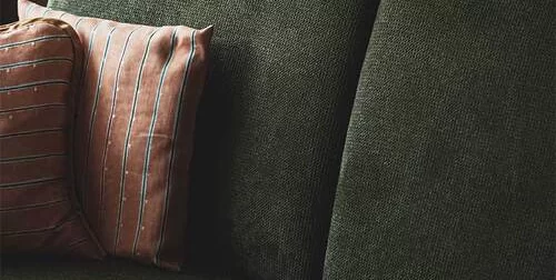 Green couch with orange cushion